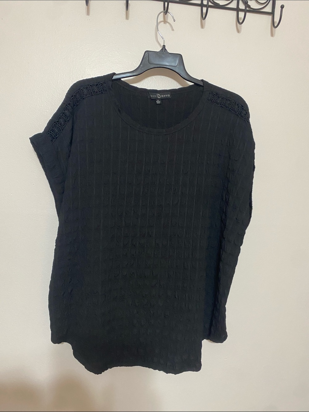 Black short sleeve top with lace detail along shoulder and cuffed sleeves